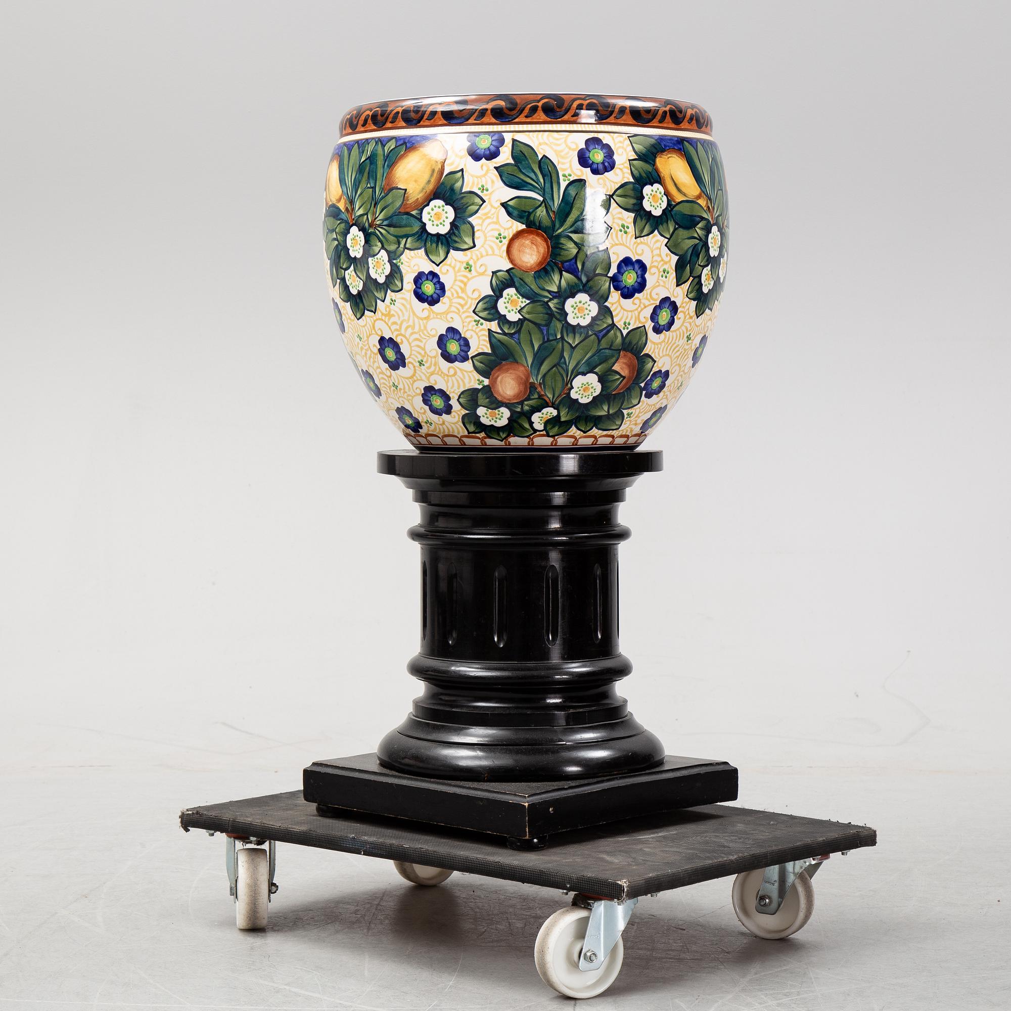 A handpainted faience, urn on wooden pedestal. Aluminia, Denmark. Dated 1910.