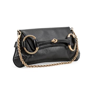 GUCCI, a black embossed leather clutch with a shoulder strap.