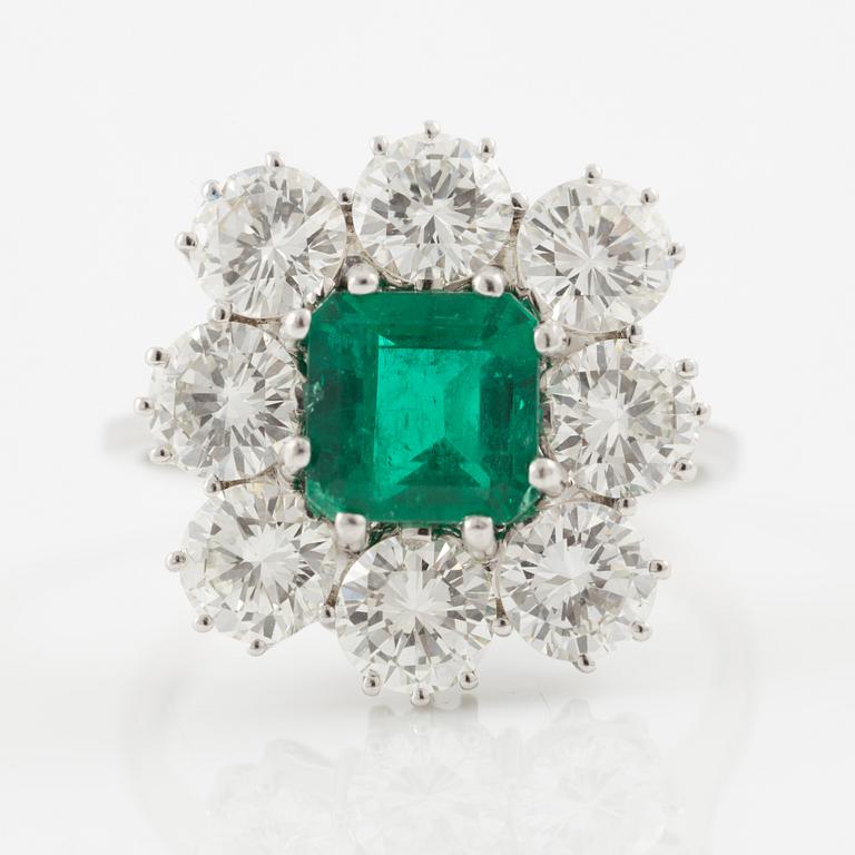An 18K whitegold ring set with a step-cut emerald and round brilliant-cut diamonds.