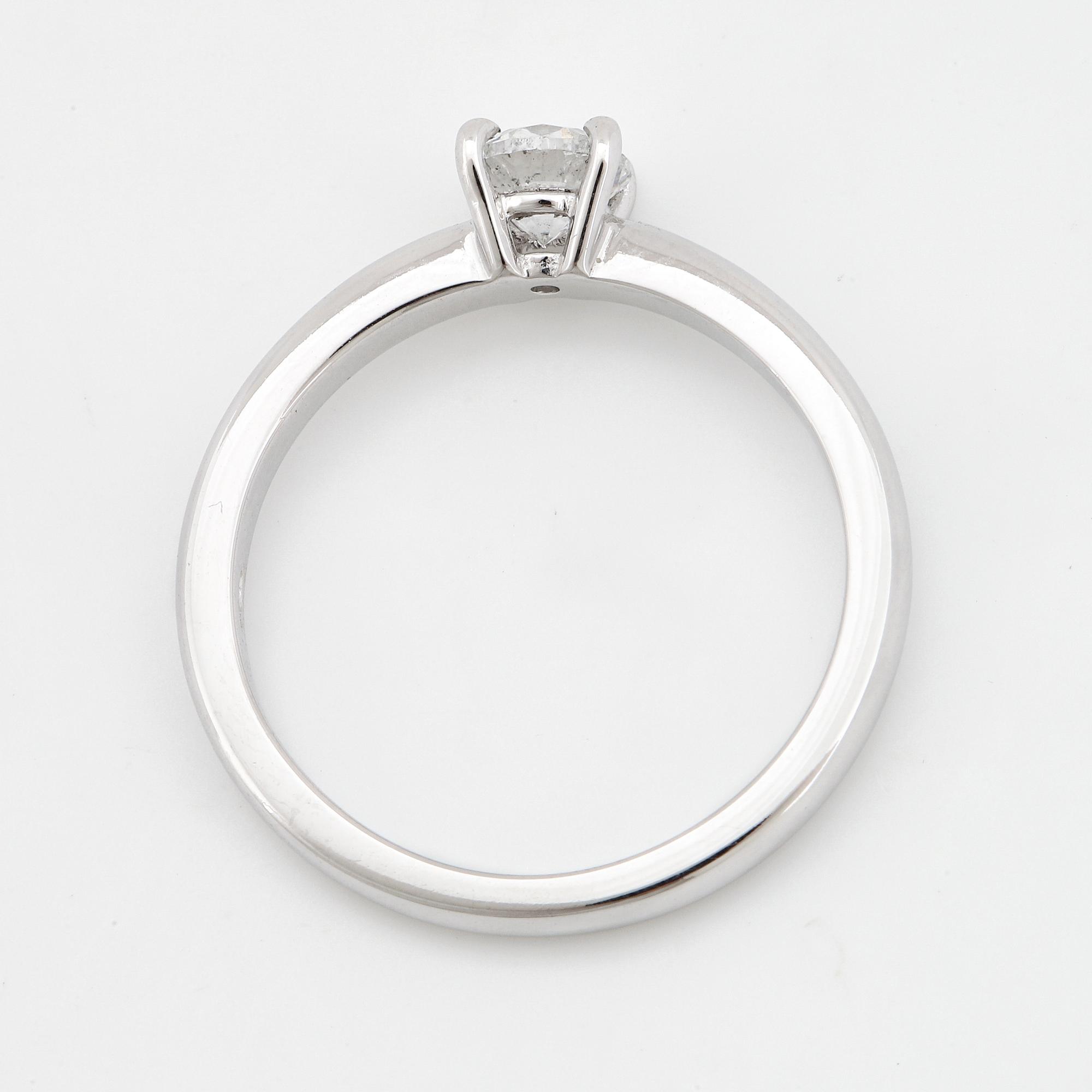 An 18K white gold ring set with a round brilliant-cut diamond.
