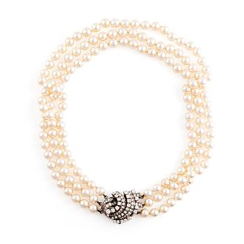 A three strand cultured pearl necklace with an 18K gold clasp set with round brilliant-cut diamonds.
