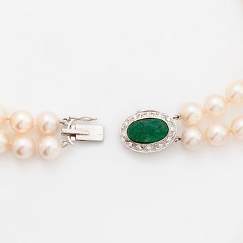 A two strand cultured pearl necklace with an 18K white gold and emerald clasp.