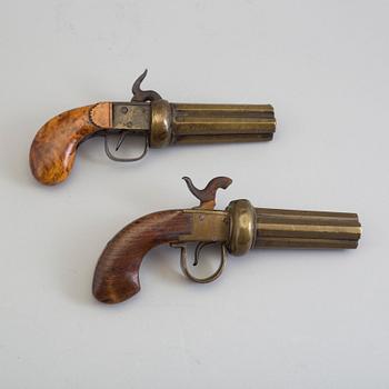 SLAGLÅSREVOLVRAR, 2 st, svenska, i mässing, fyrpipiga, varav 1 signerad.
