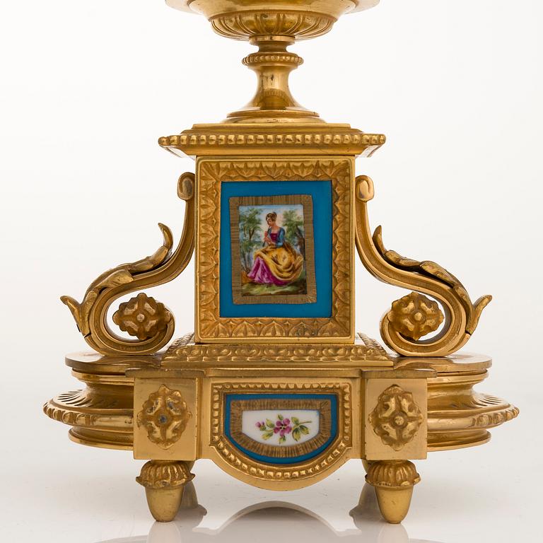 A mid-19th-century French gilt-brass mantel clock with a pair of candelabra by Dussault.