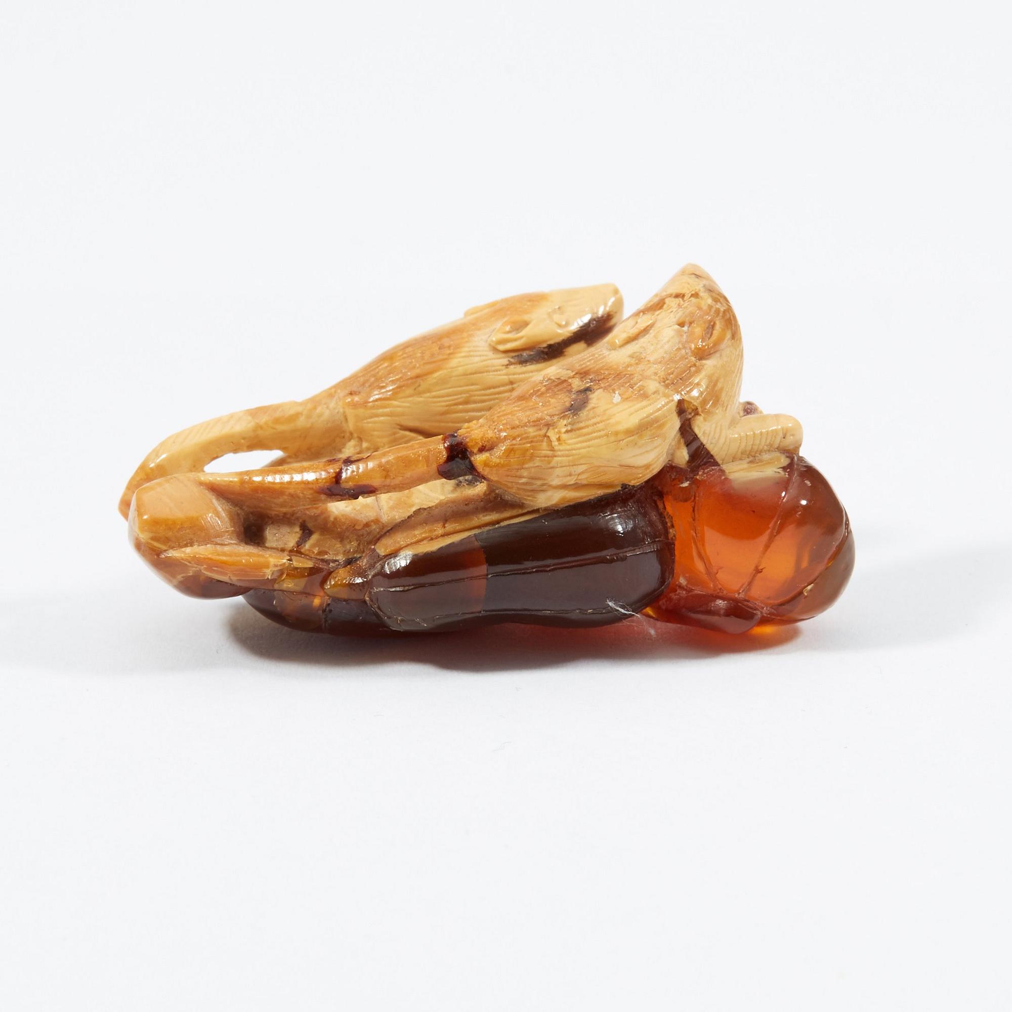 A carved amber figure/pendant of two squirrels sitting on some fruit, early 20th Century.