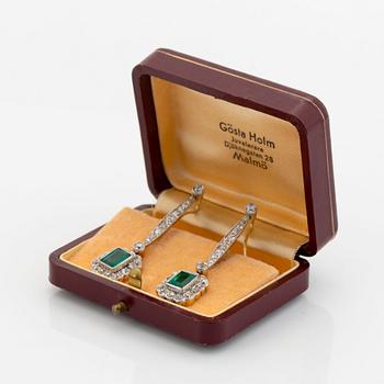 A pair of platinum and gold earrings set with step-cut emeralds and old-cut diamonds.