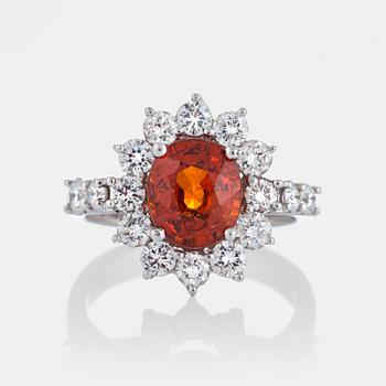 A ring set with a faceted spessartine garnet and round brilliant-cut diamonds.