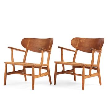 Hans J. Wegner, a pair of "CH 22" oak chairs, Carl Hansen & Son, Odense, Denmark, mid 20th century.