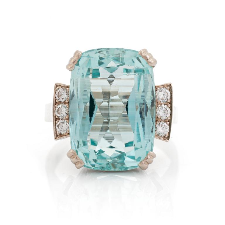 An 18K white gold ring set with a faceted aquamarine and round brilliant-cut diamonds.