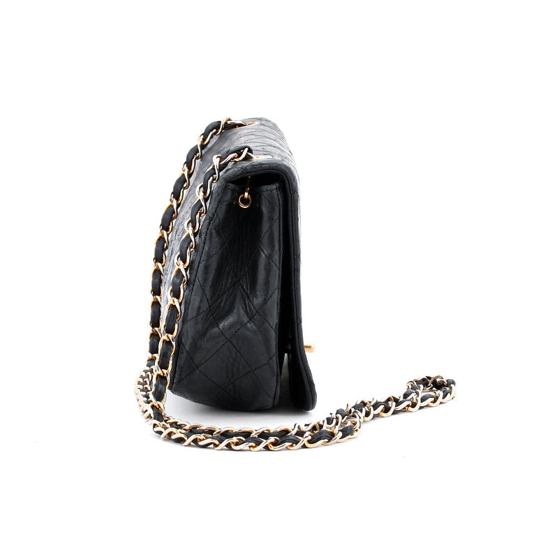 CHANEL, a black leather quilted purse with shoulder strap.