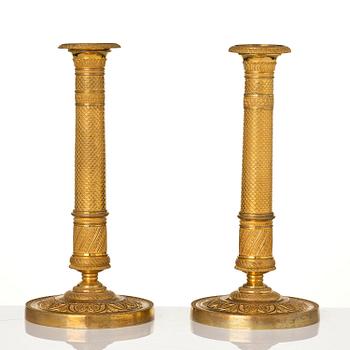 A pair of French Empire ormolu candlesticks, early 19th century.