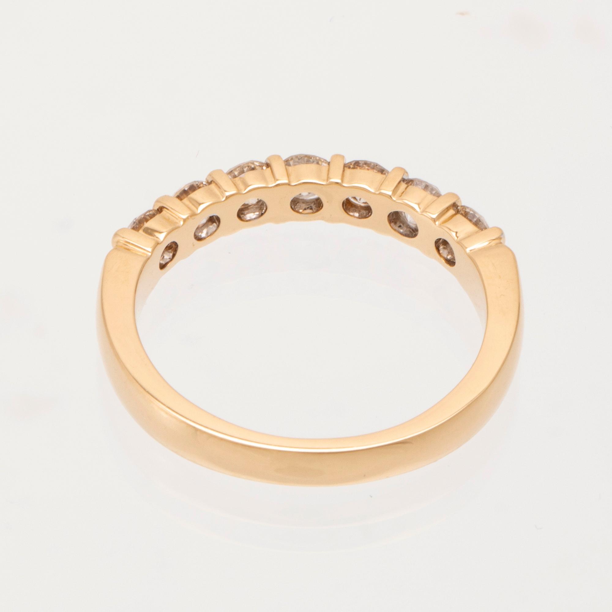 An 18K gold half-eternity ring set with round brilliant-cut diamonds.