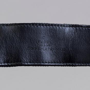 A blach monogram belt by Gucci.