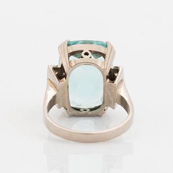 An 18K white gold ring set with a faceted aquamarine and round brilliant-cut diamonds.