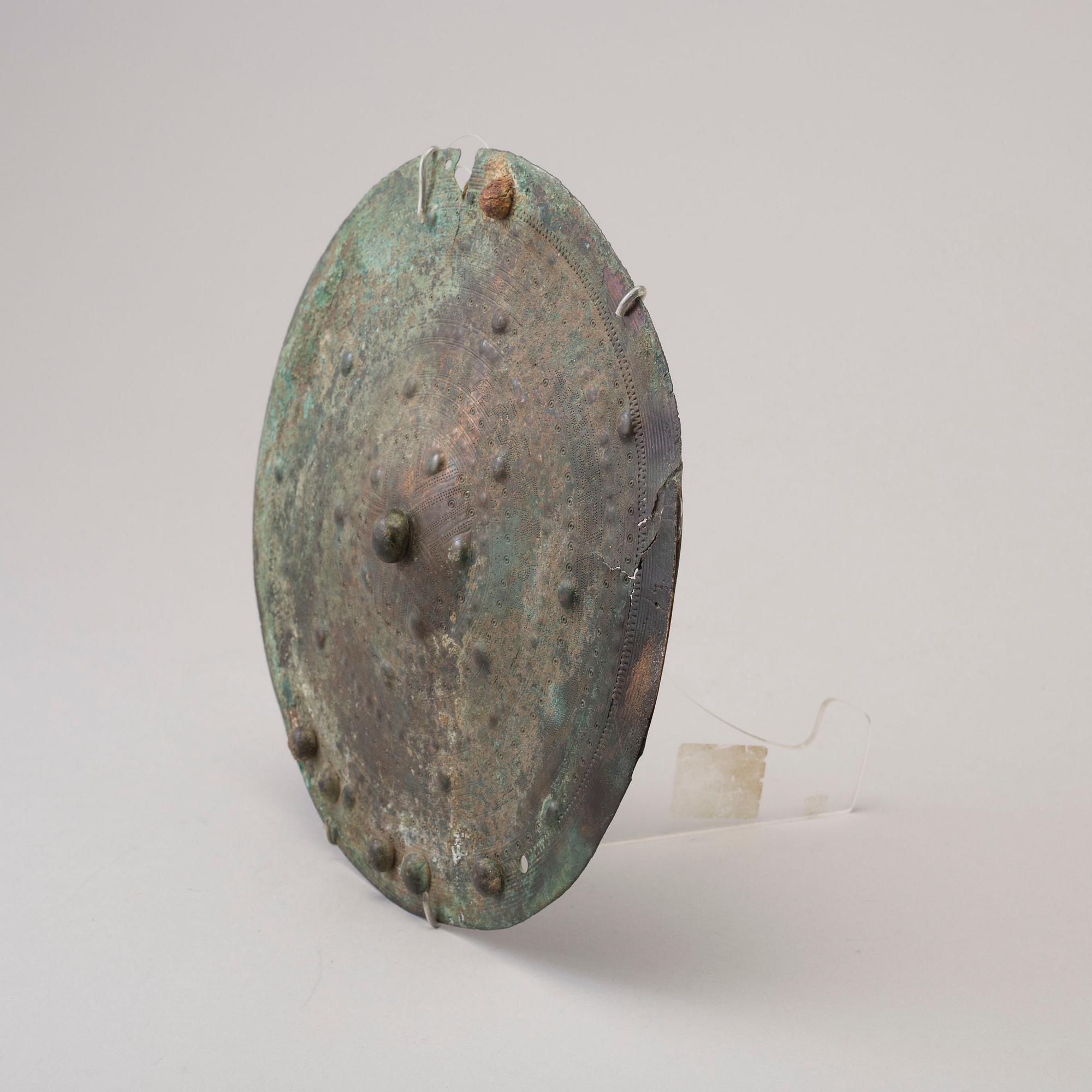 Three 20th century stone objects, with one bronze shield.