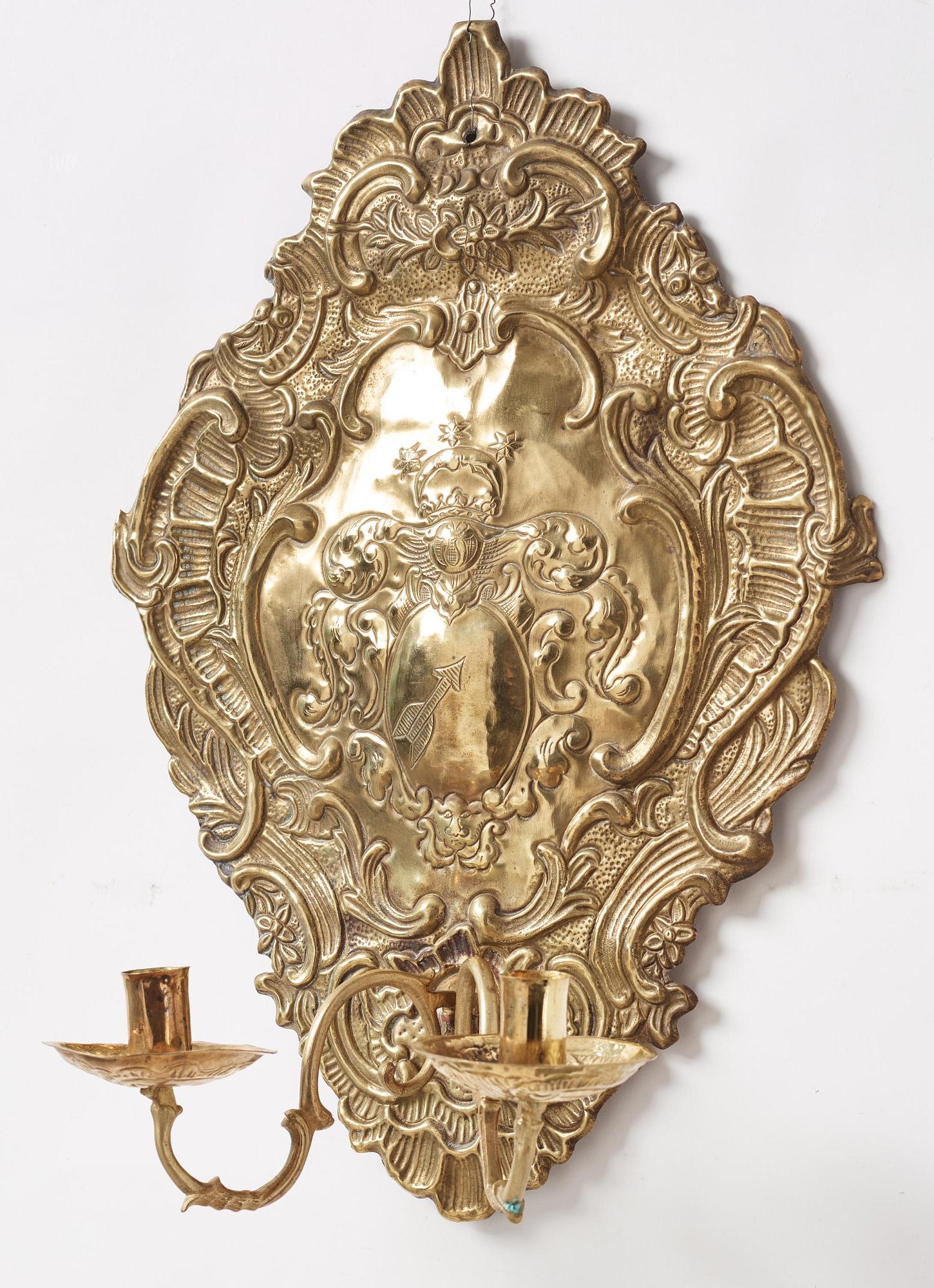 A pair of North European Rococo two-branch repoussé brass reflector plates, mid 18th century.