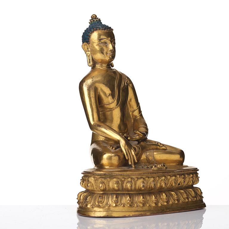 A gilt copper alloy figure of Akhsobya buddha, Tibet, 15th Century.