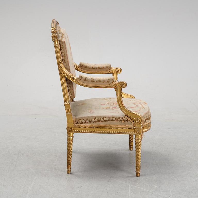 A gilt Louis XVI style armchair from around the year 1900.