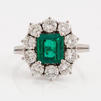 967. An 18K white gold ring set with a faceted emerald ca 1.15 cts and round brilliant-cut diamonds.