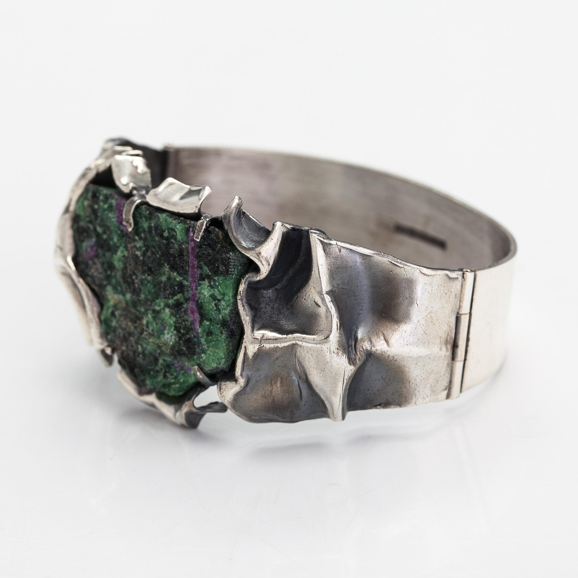 Reino Saastamoinen, Armband "Maahiset", siver och zoisit med rubinkristaller. Helsingfors 1968.