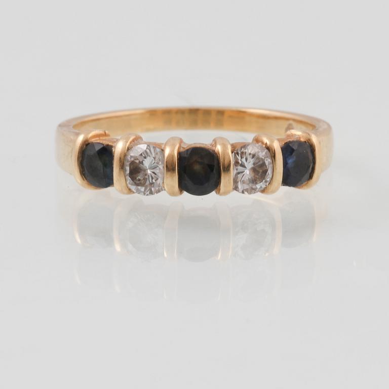 RING, 18K guld med 2 briljantslipade diamanter samt 3 fasettslipade blå safirer, kattfotstämplad. Vikt 2,9 gram.