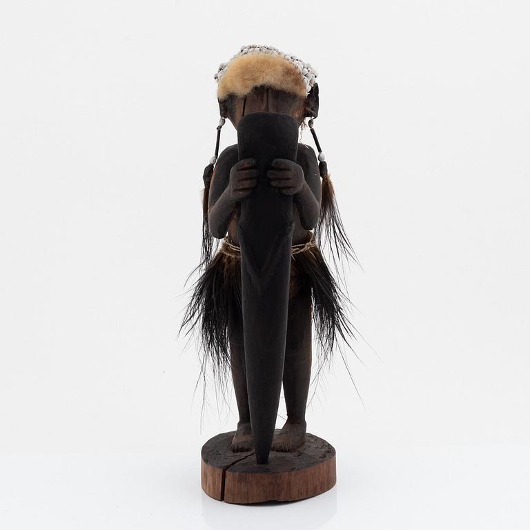 An Asmat carving of a woman holding an ax, Yamas, Jeni, 20th Century.