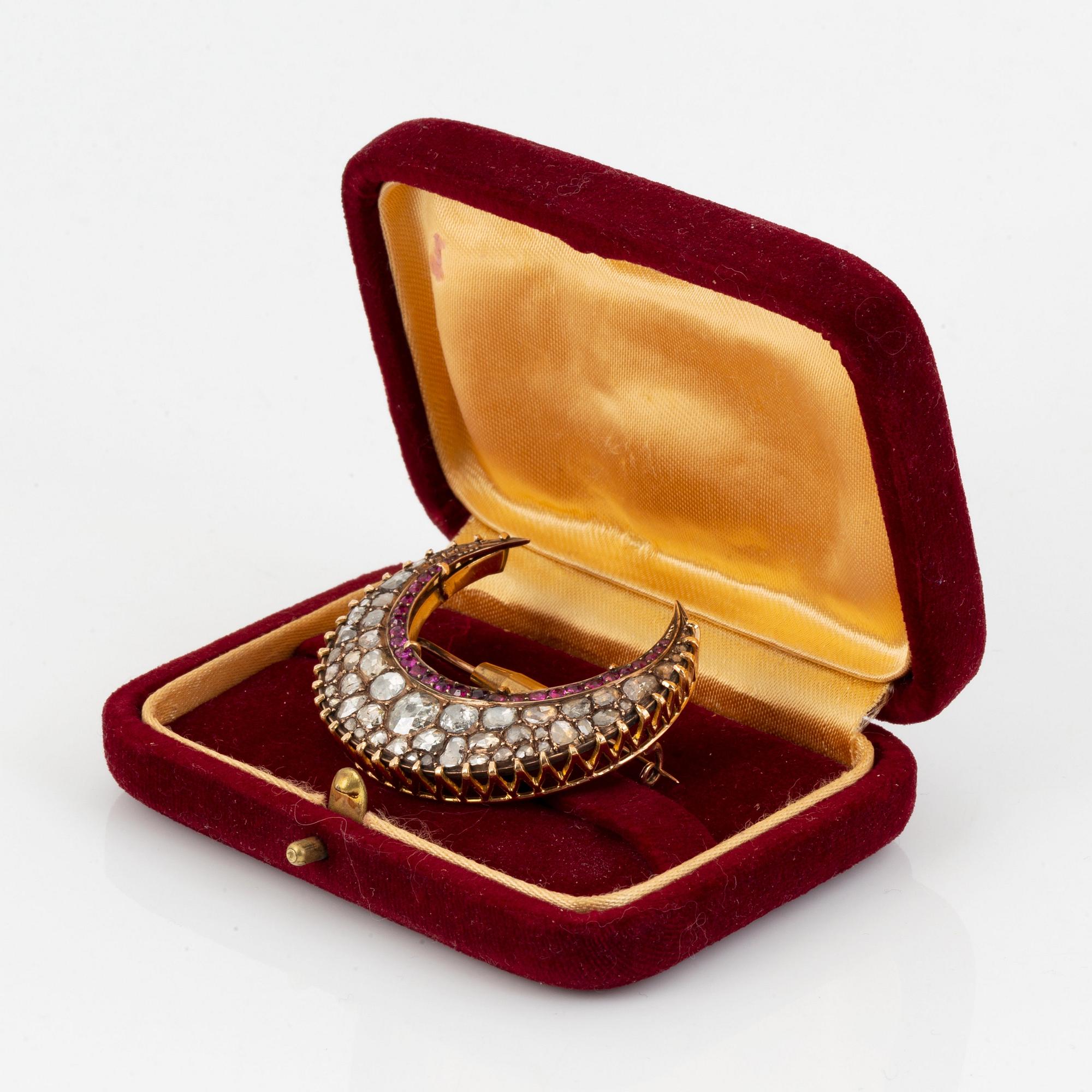Brosch guld med rosenslipade diamanter och fasettslipade rubiner i form av en halvmåne.