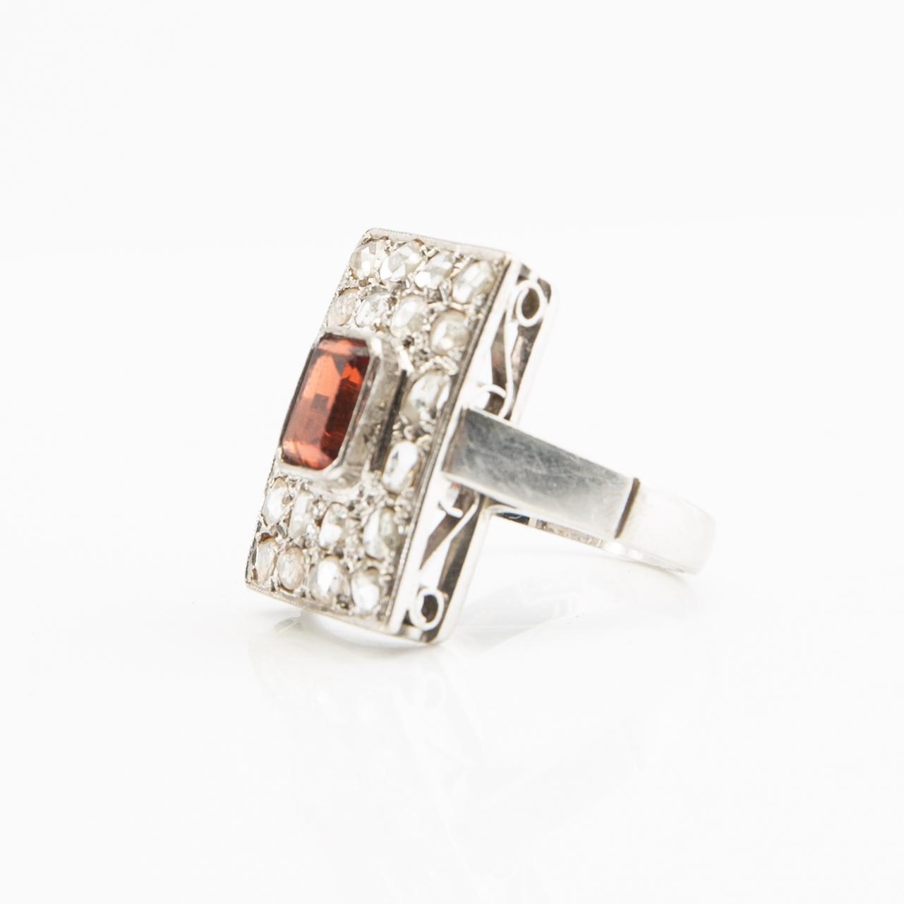 Ring, 18K white gold with a red stone (possibly garnet) and diamonds.