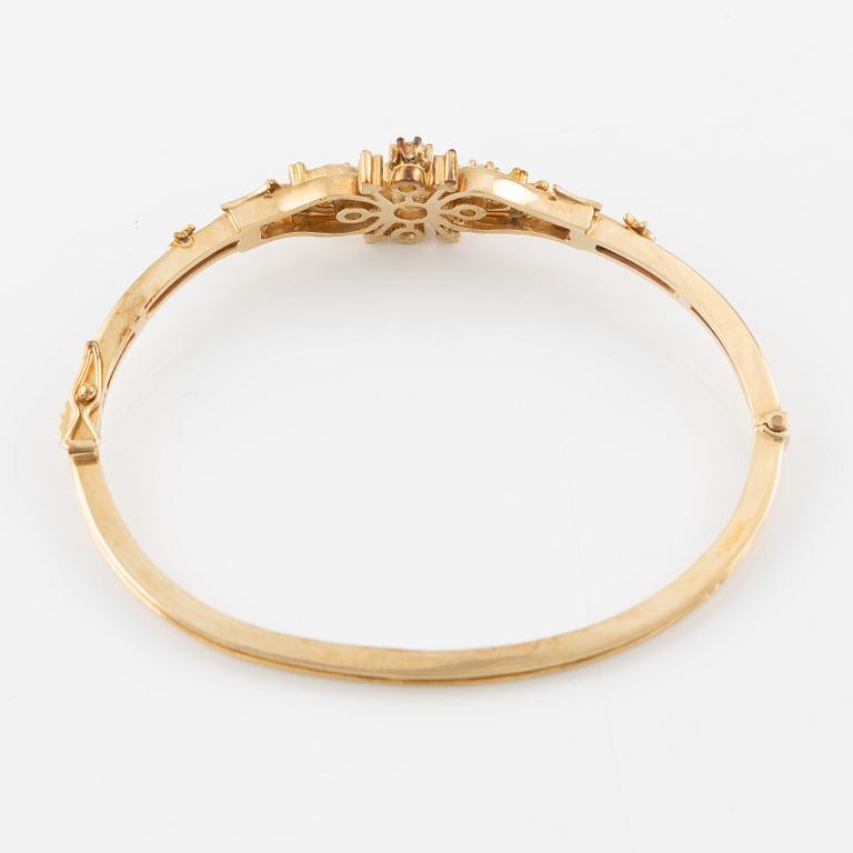 A bangle in 14K gold with round brilliant-cut diamonds.