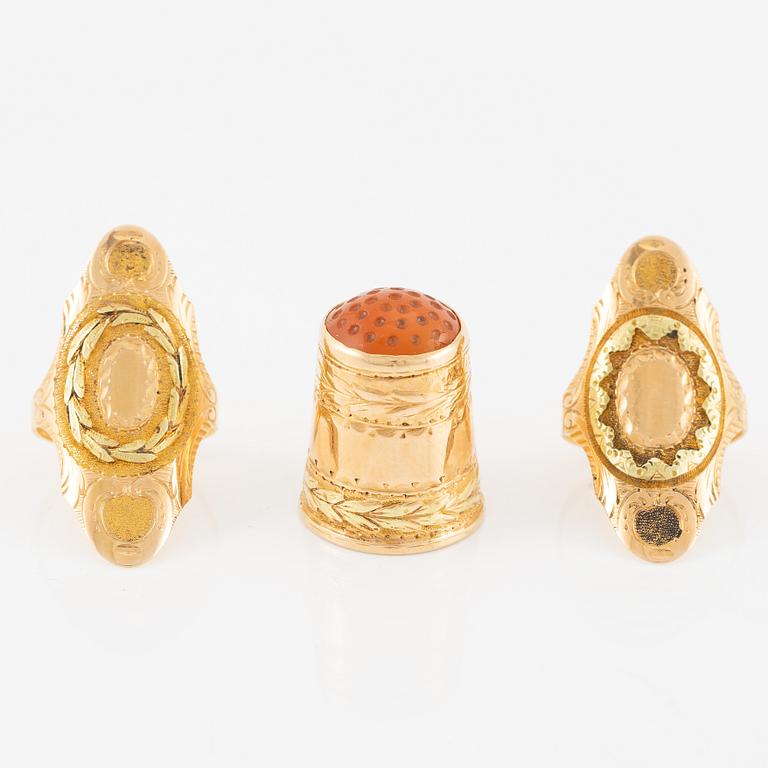 Thimble, finger guard and two rings, 18K gold, with fitted case.