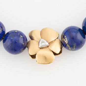 An Ole Lynggaard clasp in 18K gold with round brilliant-cut diamonds and a lapis lazuli necklace.