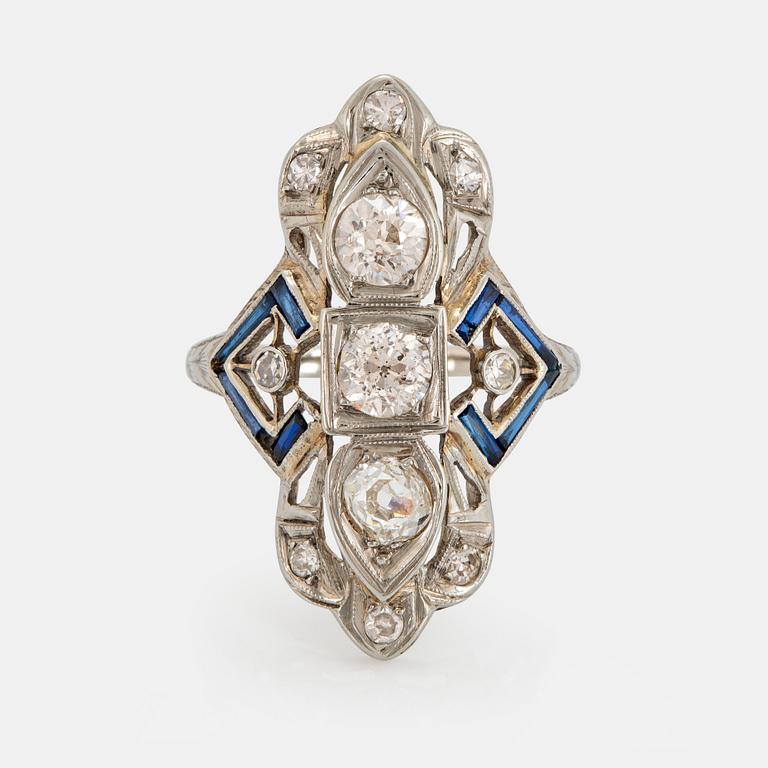 An 18K white gold ring set with old-cut diamonds and faceted sapphires, probably synthetic.