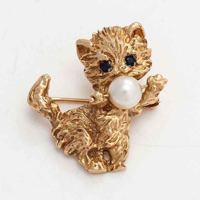 A 14K gold cat brooch, with a cultured pearl and sapphires.