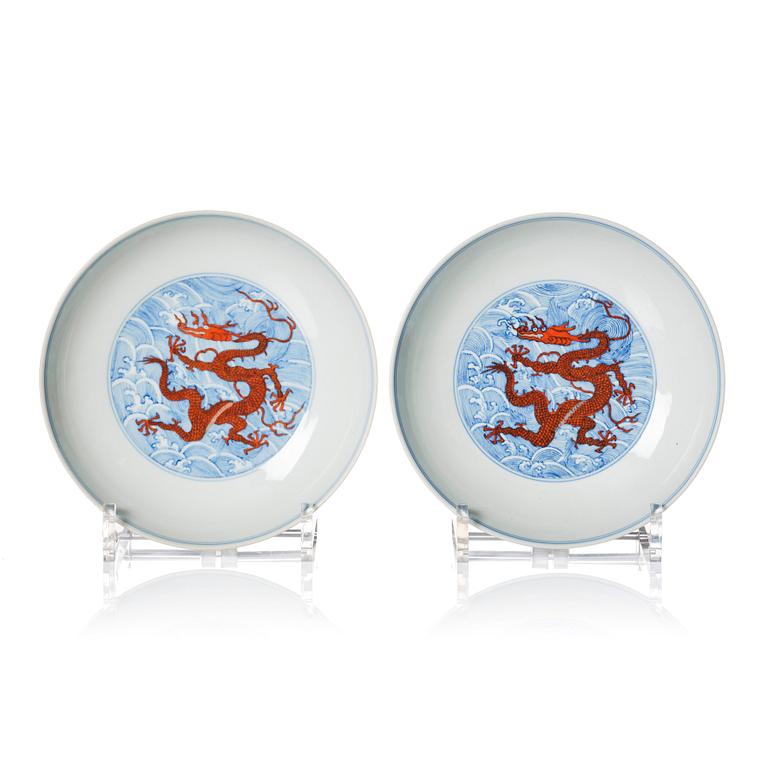 A pair of blue and white and iron red decorated dragon dishes, Qing dynasty with Qianlong mark.