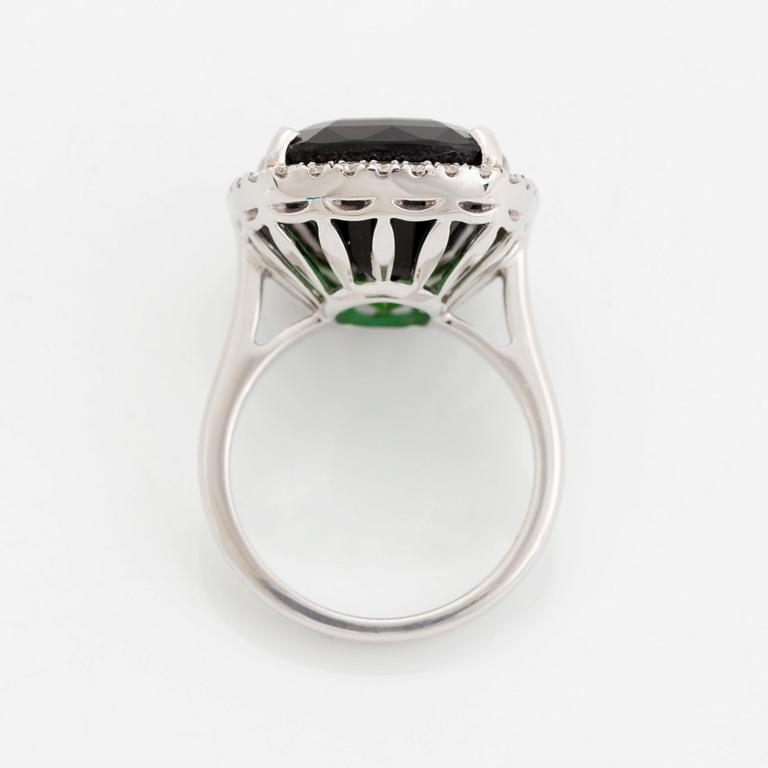 An 18K white gold ring set with a faceted green tourmaline and round brilliant-cut diamonds.