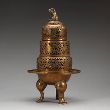 A four-part brass tripod censer, pierced sections with lotus scrolls and a fo-dog finial, late Qing dynasty (1644-1912).