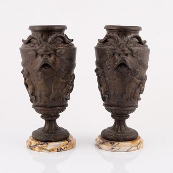 Claude Michel Clodion, after. A pair of metal vases on stone stands, signed Treta, France, early 20th Century.