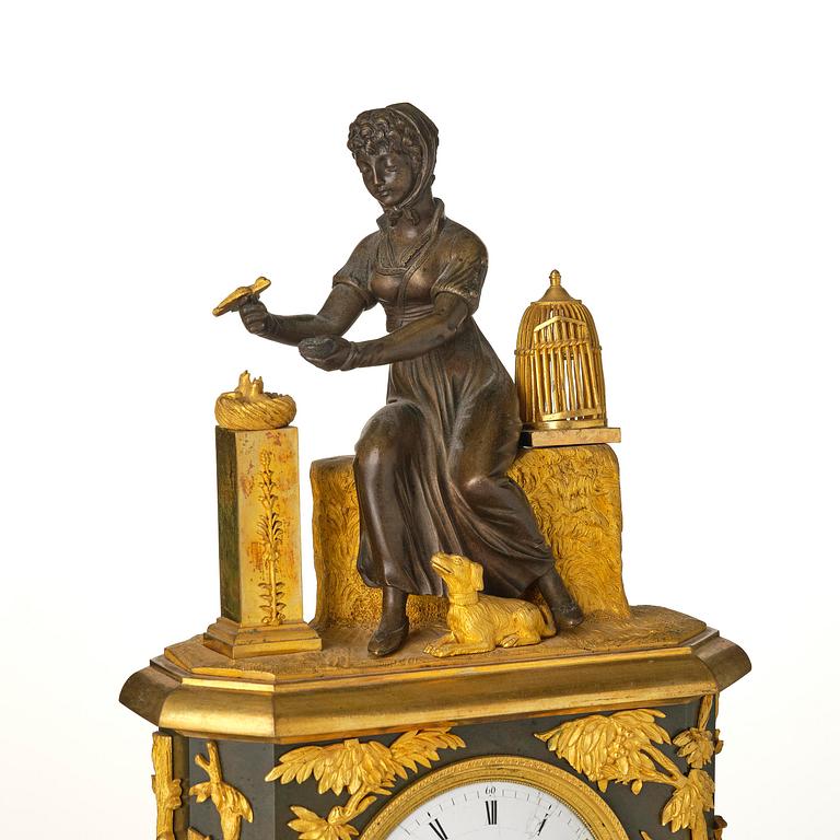 A French patinated and ormolu Directoire figural mantel clock, circa 1800.