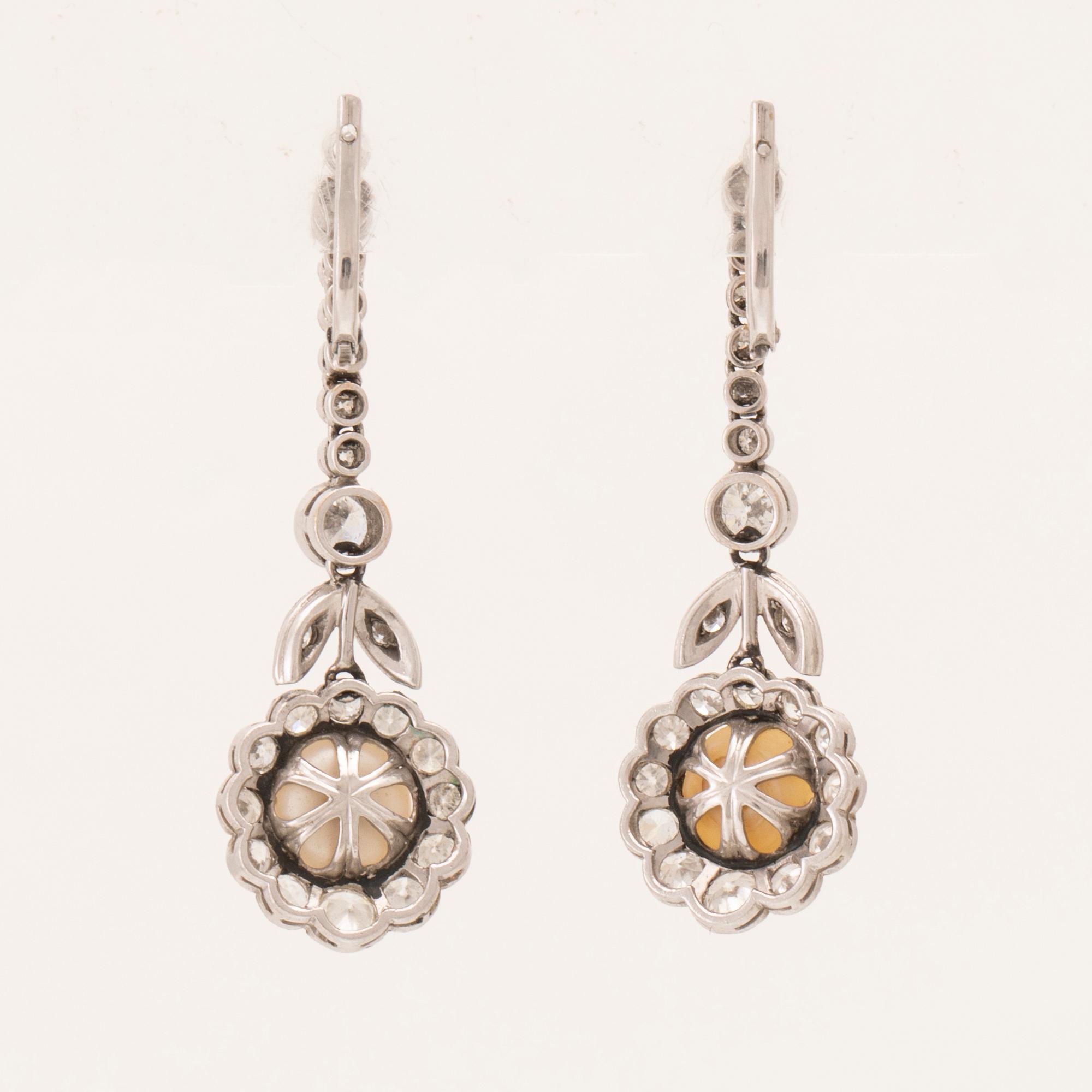 A pair of 18K white gold earrings set with cultured pearls and round brilliant-cut and old-cut diamonds.