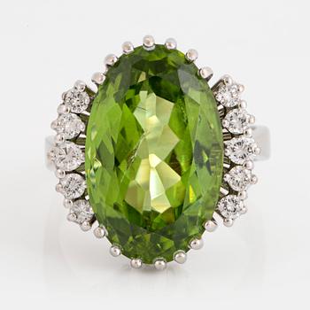 1114. An 18K white gold ring set with an oval faceted peridot ca 11.00 cts and round brilliant-cut diamonds.