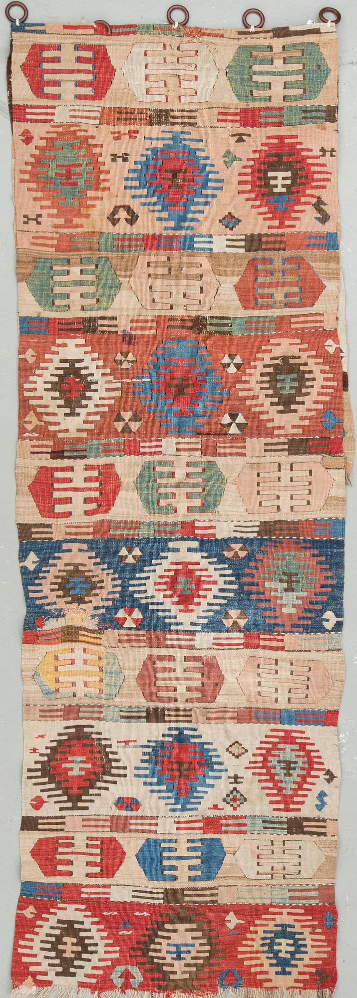 An antique Anatolian kilim fragment in form of a drape, around 232 x 76 cm.