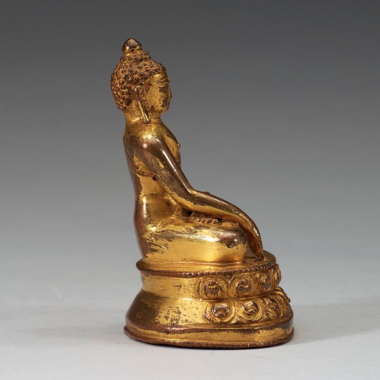 A gilt Tibetan bronze figure of Buddha, 16th Century or older.