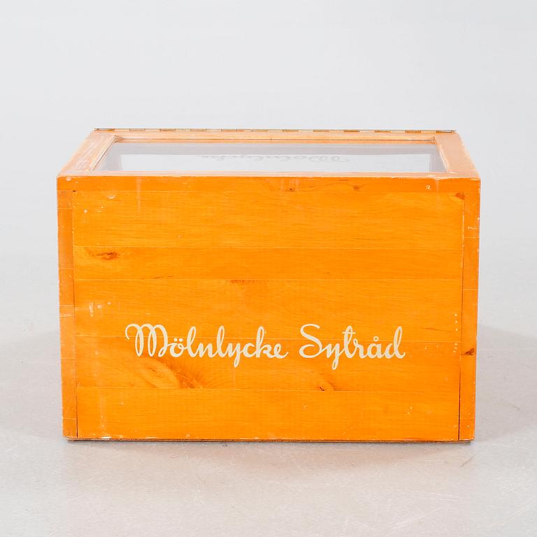 A wooden box with glass for spools of thread, mid 20th century.