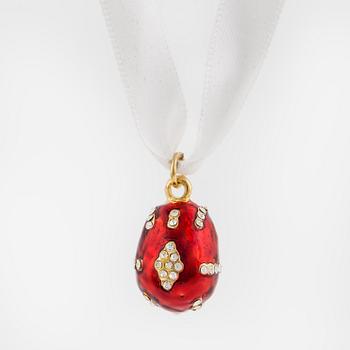 An egg-shaped pendant decorated with white paste stones to red enamel ground.