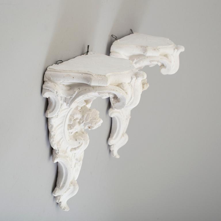 A pair of consoles and a set of three decor-elements, plaster, 20th century.