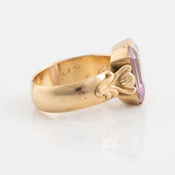 An 18K gold ring set with a pink stone.