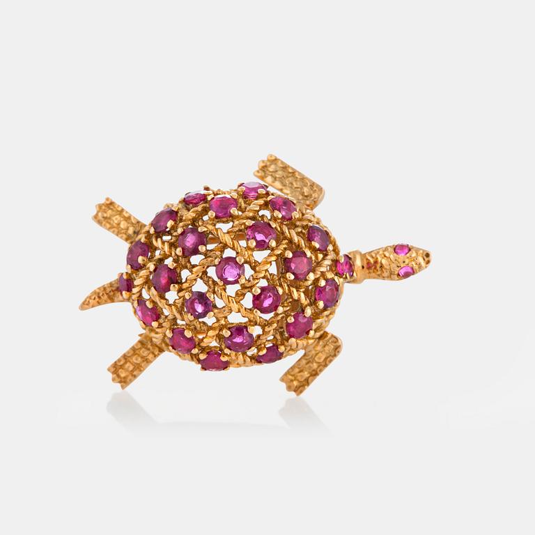 A Cartier turtle brooch in 18K gold set with rubies.