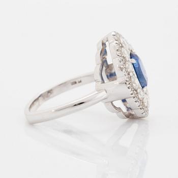 A platinum ring set with a faceted sapphire and round brilliant-cut diamonds.