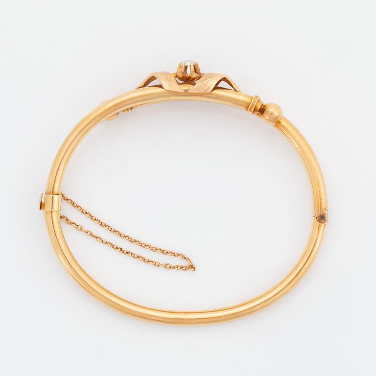 An 18K gold bangle set with a pearl.