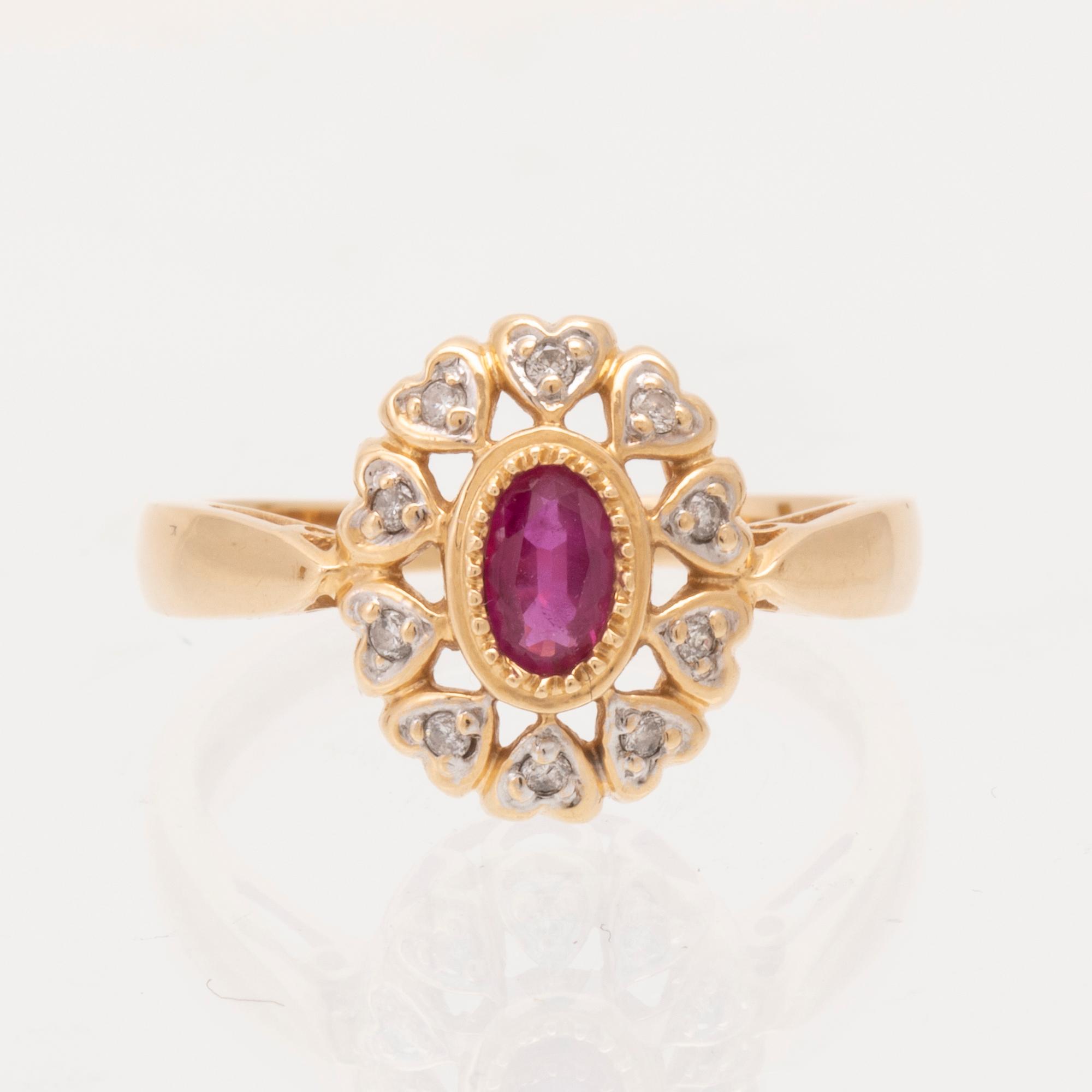 An 18K gold ring set with an oval brilliant cut ruby and round brilliant cut diamonds.